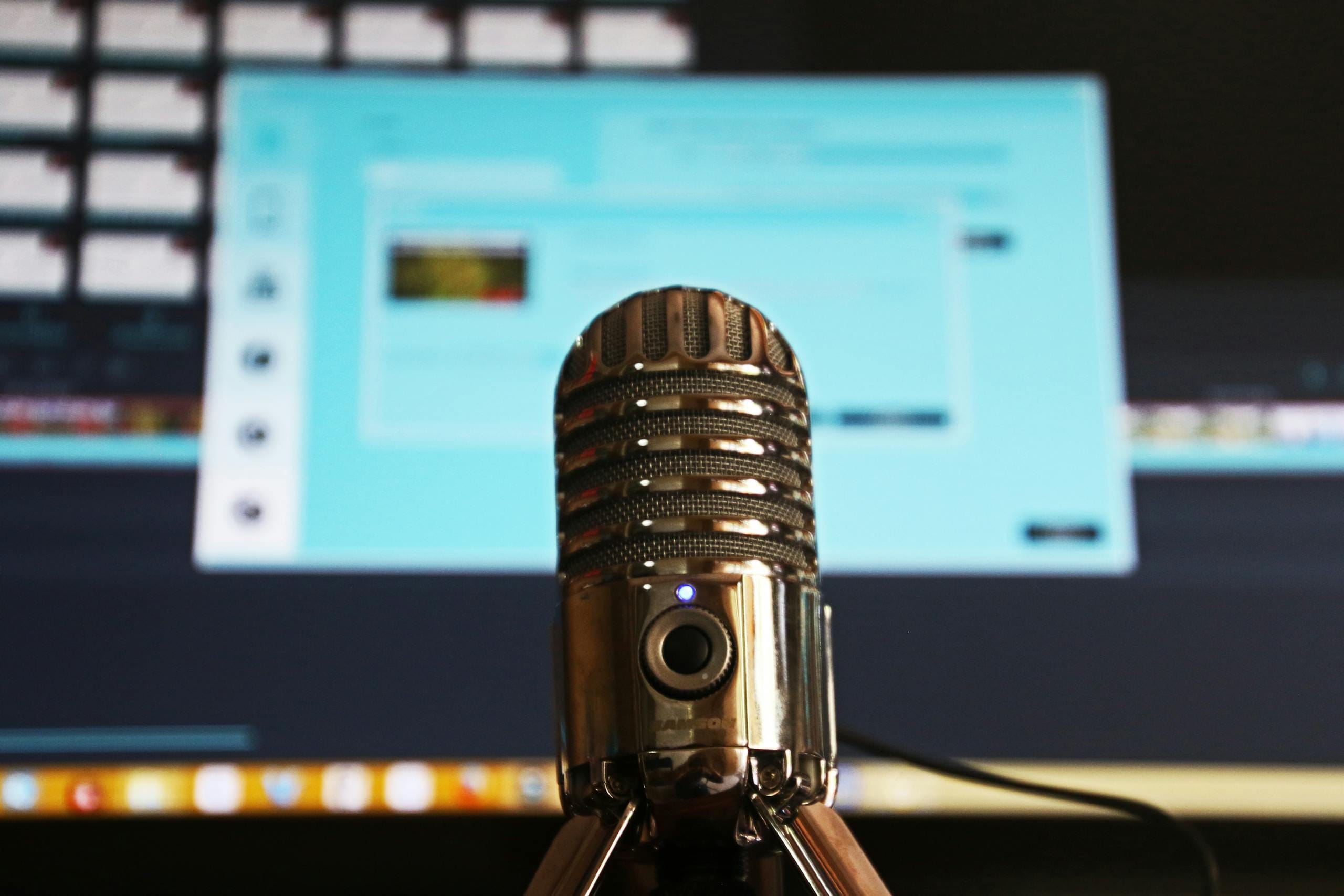 كيفية عمل فيديو طويل (لقاء بودكاست) بالذكاء الاصطناعي من الهاتف مجانًا 🤝 1 Close-up of a microphone with a blurred computer screen in the background, ideal for podcast themes.